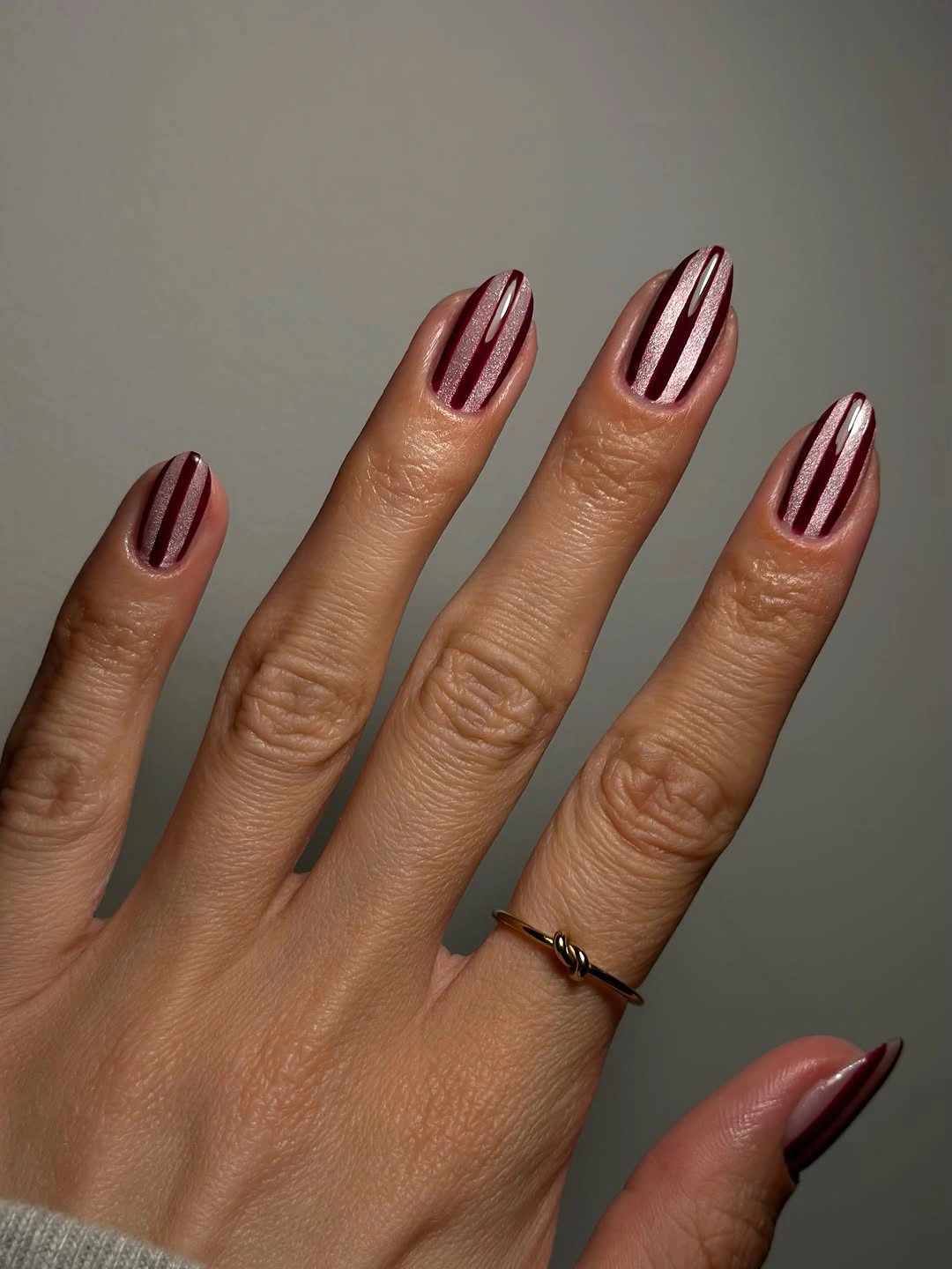 Almond pearly pink nails with narrow burgundy lengthwise stripes