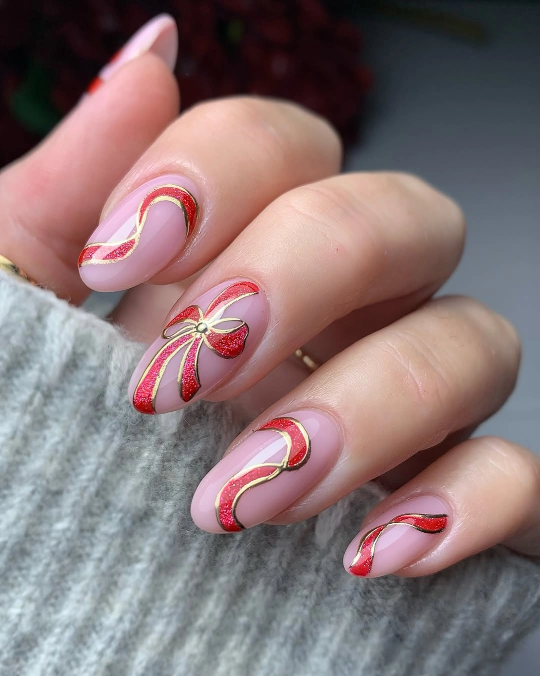 Pink almond nails with red glitter waves and gold-edged ribbon bow
