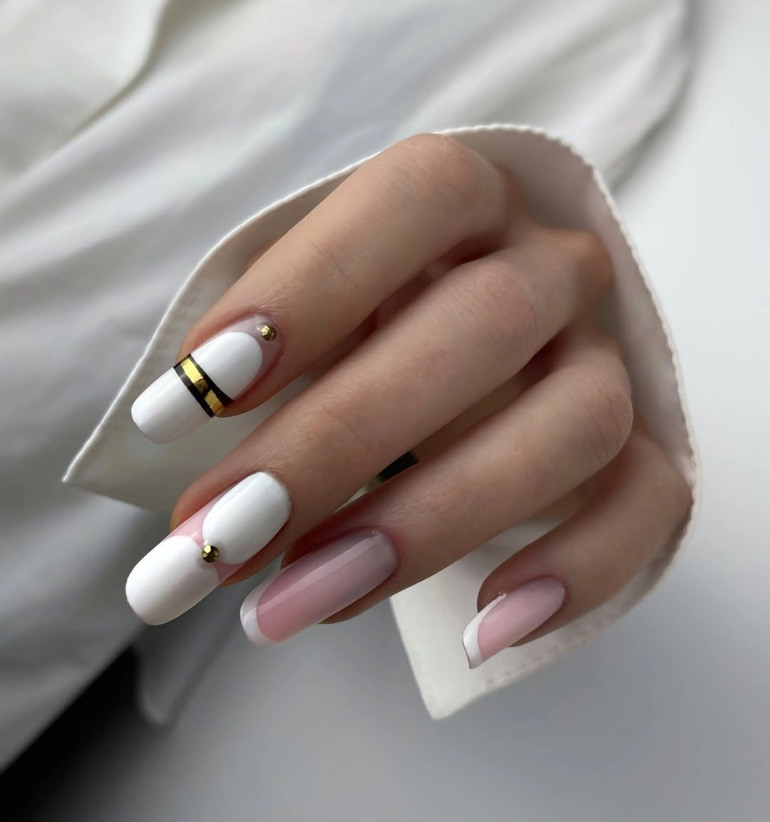 White square nails with a black and gold stripe and pale pink French tips