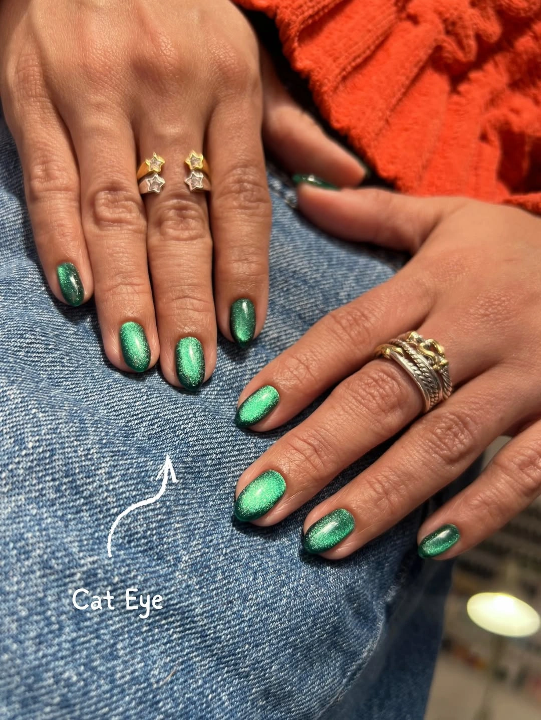 Short green nails with bright cat-eye reflections and darker edges