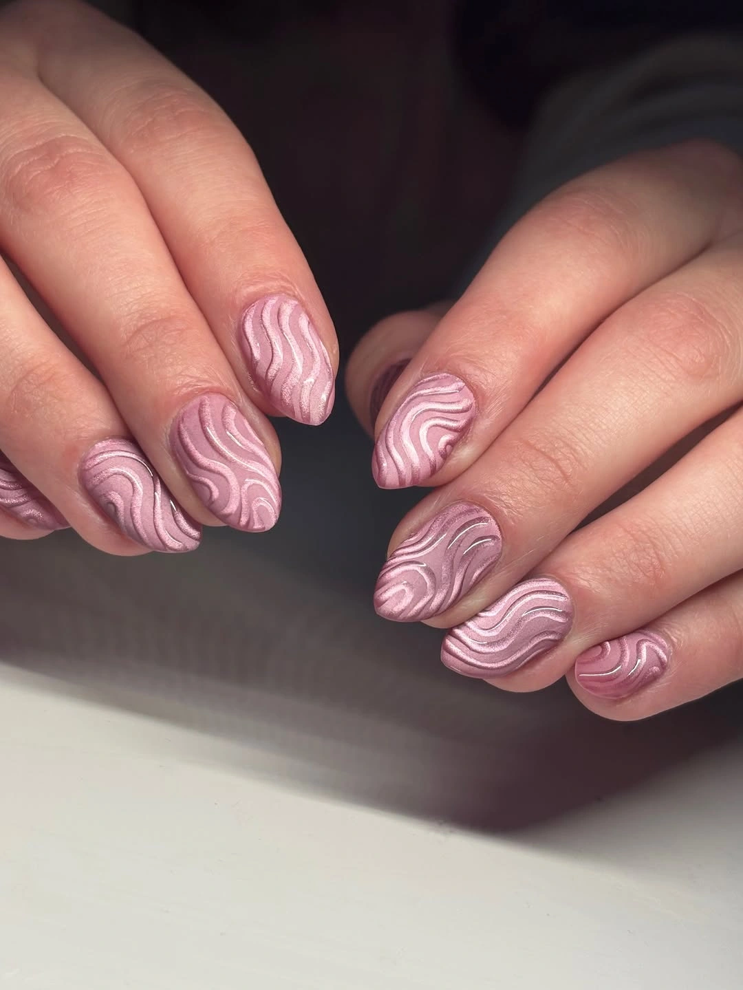 Short oval pink nails covered in raised-looking mauve and blush waves