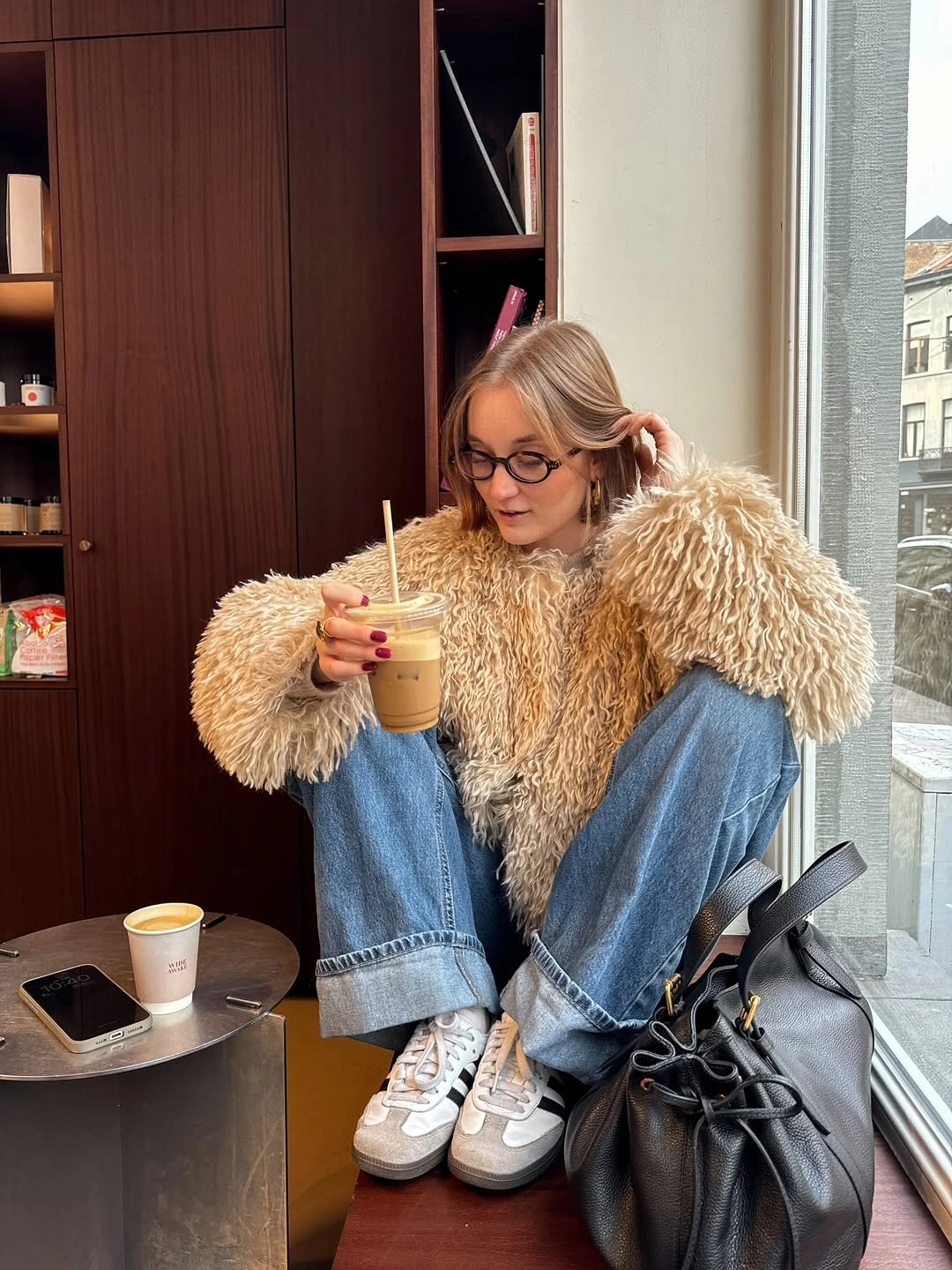 Oversized tan shaggy jacket with cuffed blue jeans and light sneakers