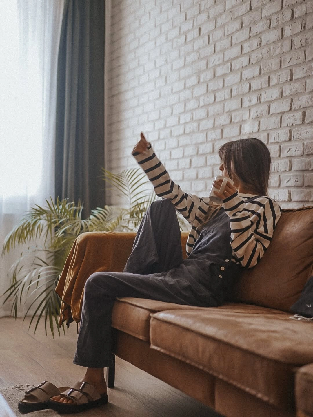 Beige and black striped top with loose dark pants and brown sandals