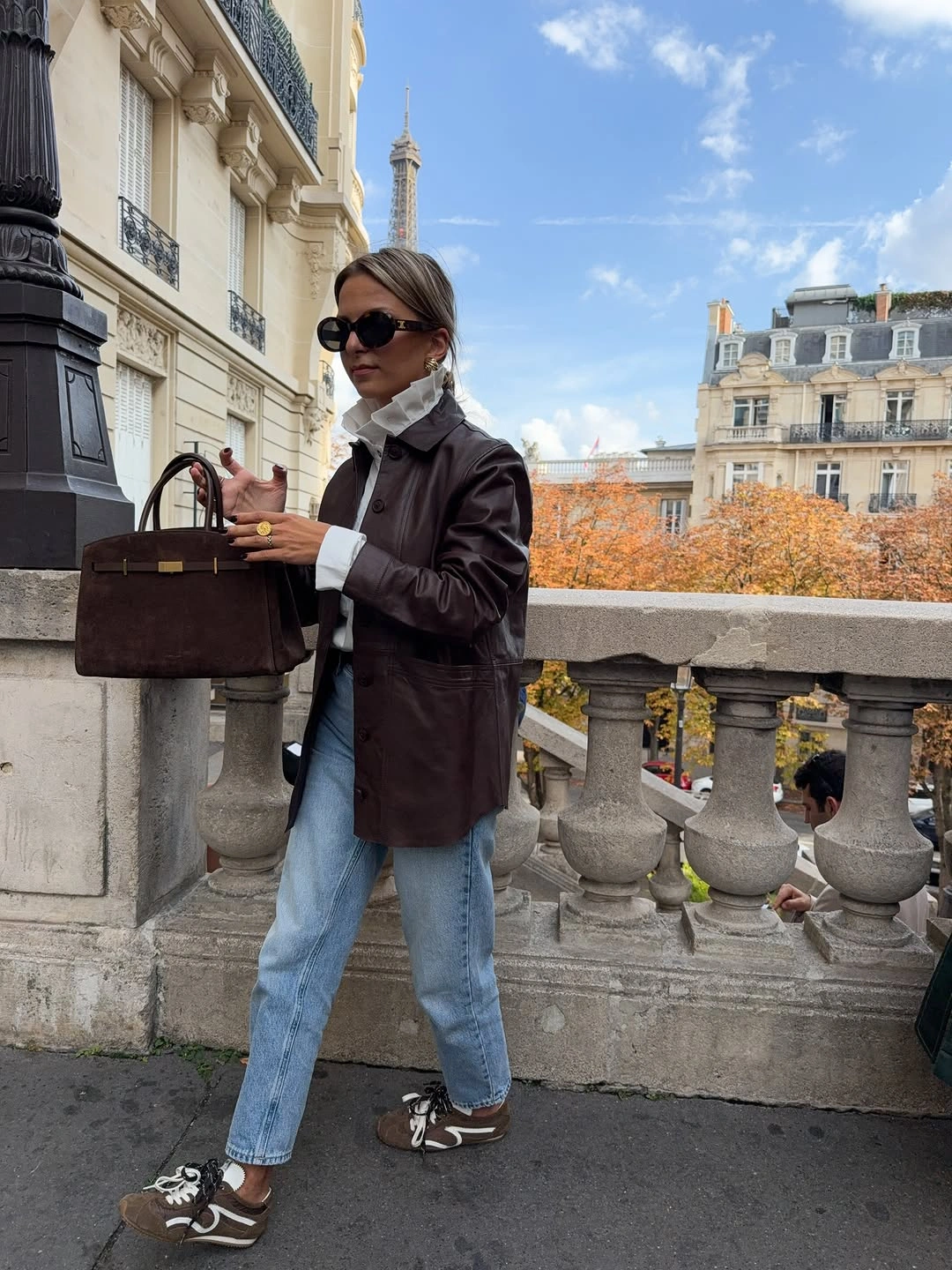 Dark brown structured jacket with white ruffled collar and light blue jeans