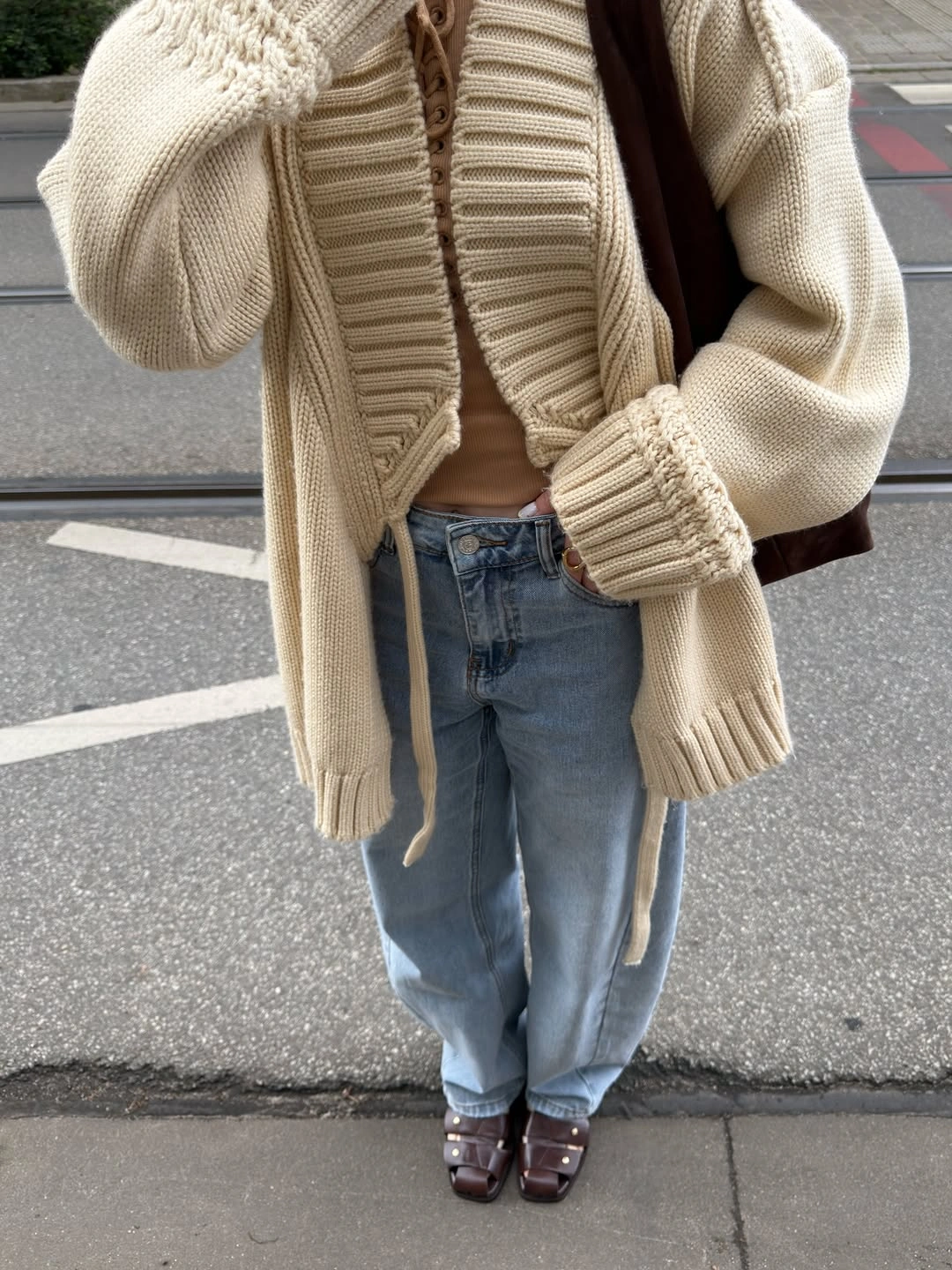 Oversized cream ribbed cardigan with tan top and relaxed blue jeans