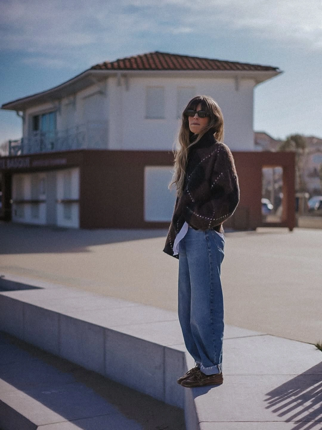 Dark high neck sweater with loose blue jeans and brown shoes