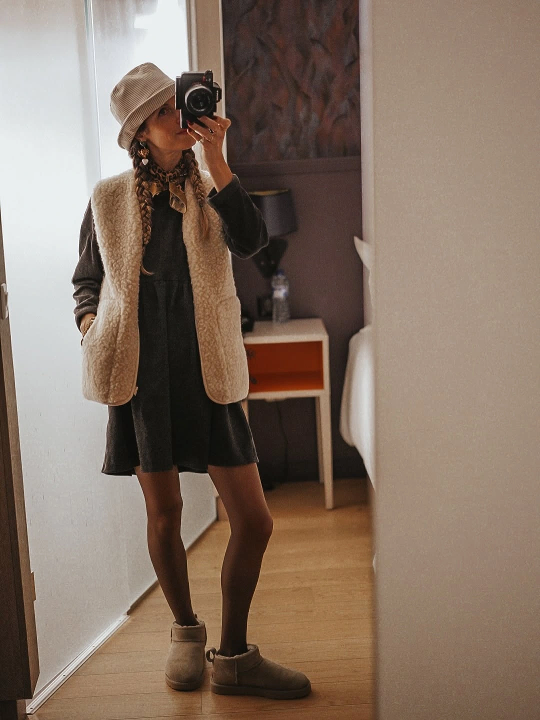 Dark long sleeve mini dress with beige textured vest and tan boots