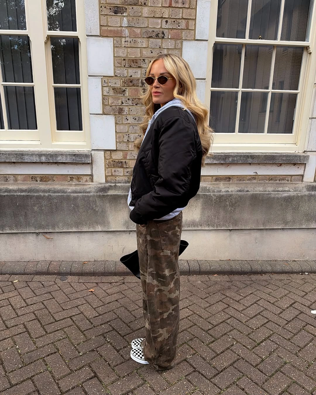 Black jacket with loose camouflage trousers and black and white sneakers