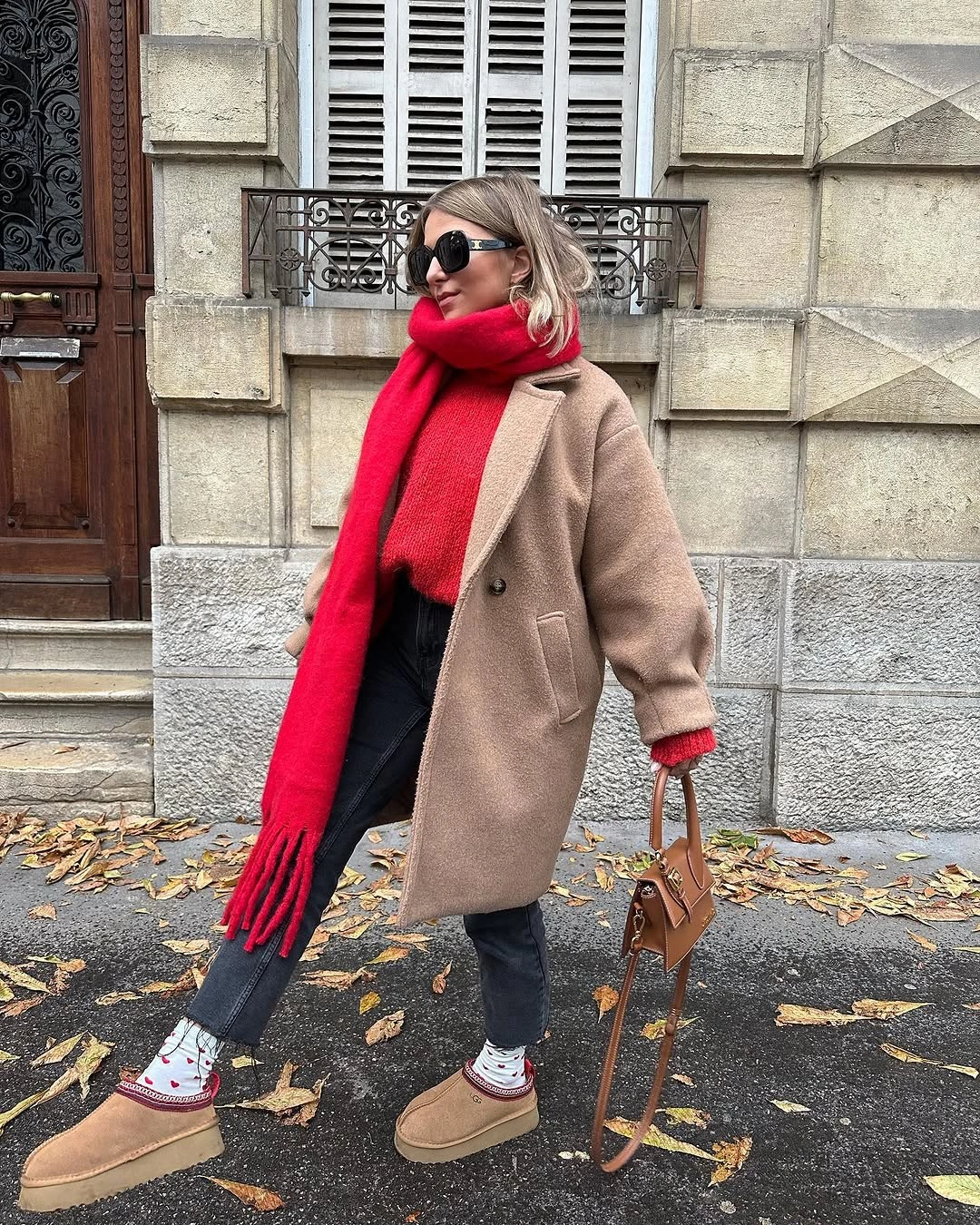 Camel coat styled with bright red scarf dark jeans and tan boots