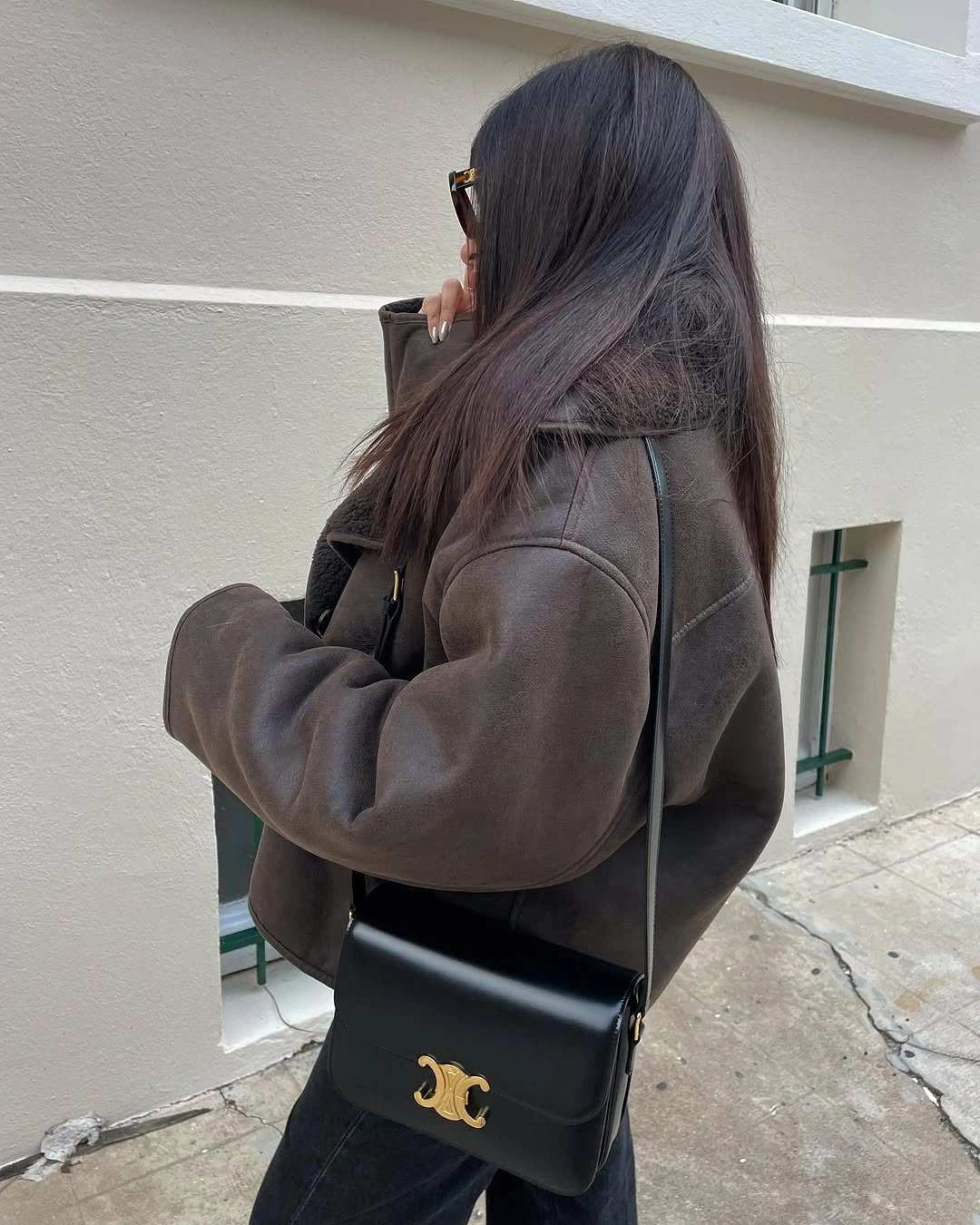 Oversized dark brown jacket with black pants and gold clasp shoulder bag