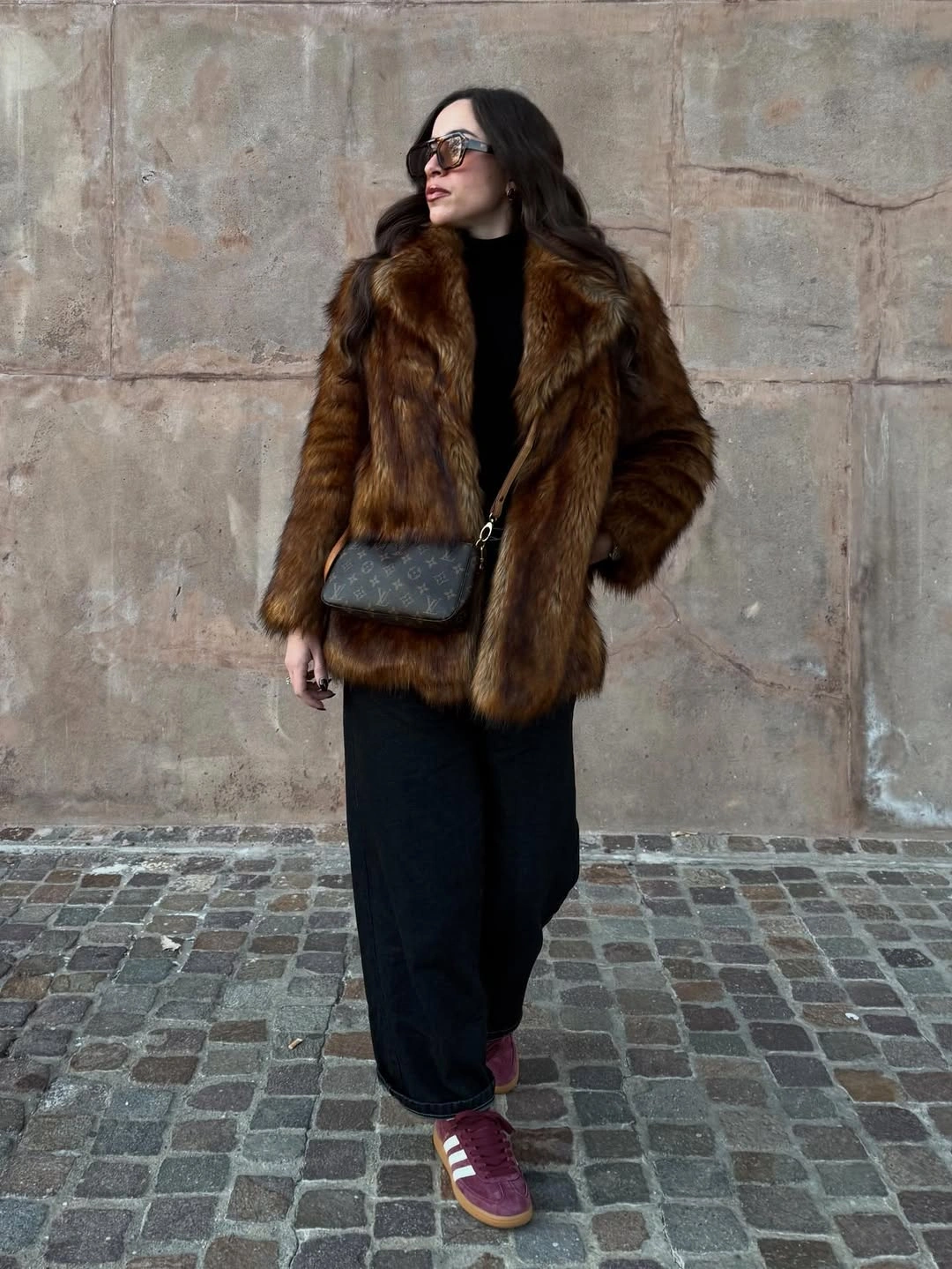 Brown shaggy jacket over black layers with burgundy sneakers